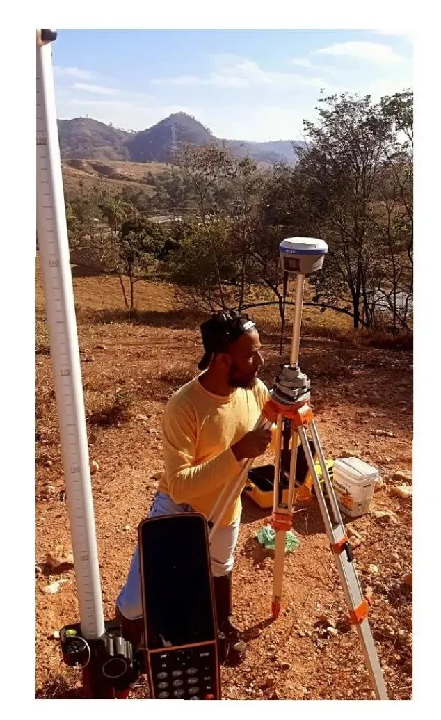 Profissional operando receptor GNSS em levantamento de imóvel rural
